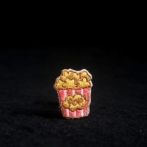 Peut inclure: Une tasse en céramique blanche avec une anse noire et le texte "But First, Coffee" en noir, en gras. La tasse est posée sur une surface blanche.