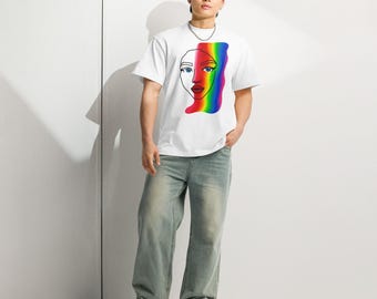 Op de afbeelding: Wit t-shirt met een minimalistisch gezichtsontwerp en een regenboogstreep. Het t-shirt wordt gecombineerd met lichtblauwe jeans. De persoon draagt zwart-wit gestreepte schoenen.