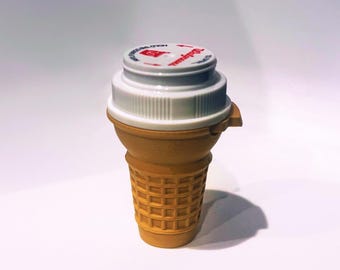May include: A white ceramic mug with a black handle and the text "But First, Coffee" in a bold, black font. The mug is set against a neutral background, highlighting its simple design.