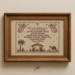 Könnte beinhalten: Ein gerahmtes Kreuzstich-Wandbild auf beigem Stoff mit dem Text For to us a child is born, to us a son is given; and the government shall be upon His shoulder, and His name shall be called Wonderful Counselor, Mighty God, Everlasting Father, Prince of Peace Isaiah 9:6, mit gestickten Engeln, einer Palme, einer Krippenszene und einem Kamel.