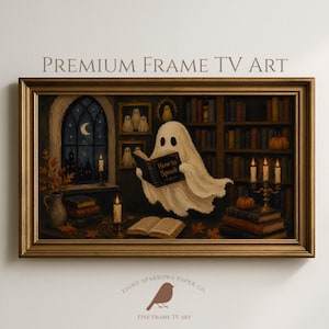 May include: A rectangular gold-toned frame containing digital art of a white ghost reading a book titled How to Spook in a library. The scene includes bookshelves, a window with a crescent moon, lit candles, pumpkins, and framed ghost portraits.