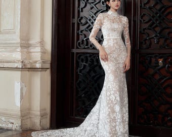 Vestido de novia de encaje estilo sirena con cuello alto, manga larga y encaje floral en 3D.