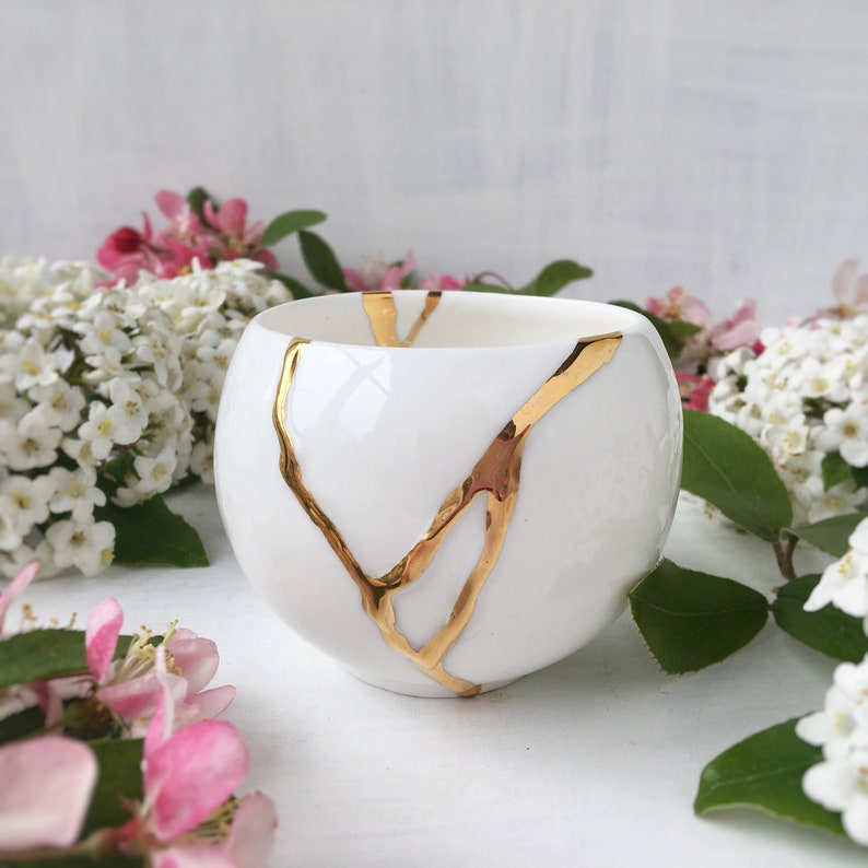 Spherical shaped white porcelain teacup decorated with golden veins. Inspired by ancient Japanese art of repairing ceramics.