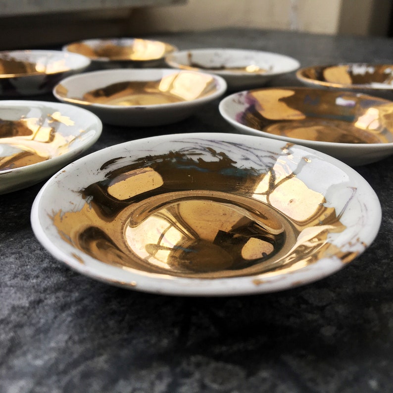 K&ouml;nnte beinhalten: Ein Set kleiner, wei&szlig;er Keramikschalen mit goldenen Akzenten. Die Schalen haben eine leicht unregelm&auml;&szlig;ige Form und eignen sich perfekt zum Servieren kleiner Snacks oder Desserts.