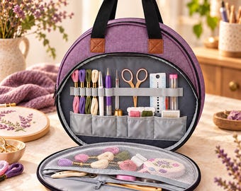 Può includere: Una borsa rotonda in tessuto viola con manici neri e dettagli marroni. La borsa aperta rivela passanti elastici interni che contengono fili da ricamo, forbici e strumenti, oltre a una tasca con cerniera in rete.