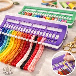 May include: A close-up of two thread organizers filled with colorful embroidery floss. The front organizer is purple with white accents and holds a rainbow of threads. The second organizer is green. Gold scissors are in the background.