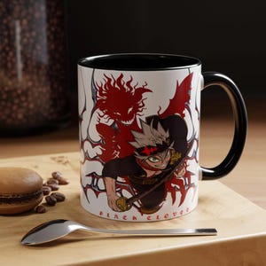 May include: Black Clover coffee mug with a black handle and rim. The mug features a detailed illustration of an anime character with red and black accents. The words "Black Clover" are printed on the mug.