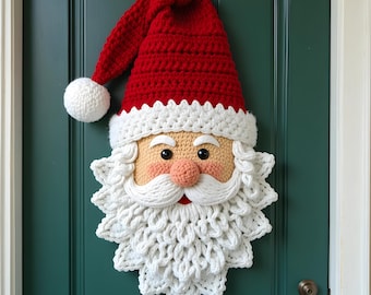 Può includere: Decorazione per porta fatta a mano all'uncinetto con la faccia di Babbo Natale. Il volto di Babbo Natale presenta un cappello rosso con un pompon bianco, una barba bianca e un viso rosato. La decorazione è appesa a una porta verde acqua.