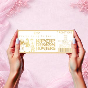 Puede incluir: Un boleto dorado con el texto "Eric" y "K-Pop Demon Hunters". El boleto dice "Admite uno" e incluye un mensaje para un octavo cumpleaños. El boleto se sostiene sobre un fondo rosa.