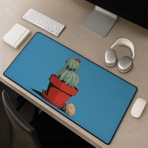 Può includere: Un tappetino da scrivania rettangolare con sfondo blu e un'illustrazione centrale di un cactus verde, spinoso e a due livelli piantato in un vaso rosso, accompagnato da una piccola pietra marrone vicino alla base.