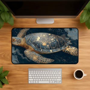 May include: A rectangular mousepad featuring a detailed illustration of a sea turtle. The turtle has a blue and gold shell, with matching flippers. The background is a dark blue with gold accents, creating a celestial effect. The mousepad is on a wooden desk.