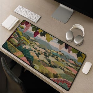 May include: A rectangular mousepad featuring a detailed landscape scene with rolling hills, vineyards, and grape vines. The color palette includes greens, browns, and blues, creating a pastoral aesthetic. A keyboard, headphones, and mouse are also visible.