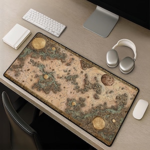 May include: A rectangular desk mat featuring a detailed, vintage-style map illustration with beige, brown, and muted green topographical patterns, circular planetary or moon motifs, and a decorative border, laid out on a wooden desk surface.
