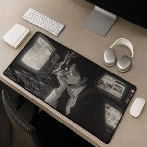 May include: Black and white mousepad featuring an anime-style illustration of a person smoking, wearing glasses, and looking at computer screens. A keyboard, mouse, headphones, and notepad are also on the desk.