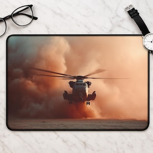 Puede incluir: Alfombrilla de ratón rectangular con un helicóptero en vuelo, sobre un fondo de polvo naranja y marrón. Las aspas del helicóptero están borrosas, lo que indica movimiento. La alfombrilla tiene un borde negro.