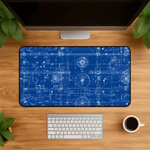 May include: A rectangular desk mat featuring a deep blue background with white technical blueprint lines, geometric shapes, and mechanical schematics printed across the entire surface. The mat has a smooth finish and black stitched edges.