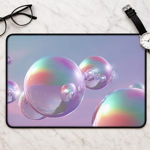 May include: A rectangular mousepad featuring a digital art design of iridescent bubbles against a soft purple and blue gradient background. The bubbles have a reflective, glass-like appearance, with rainbow-colored highlights. The mousepad has a black border.