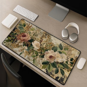 May include: A rectangular desk mat featuring a printed design of blooming flowers in shades of dusty rose, cream, and white, accented with dark green foliage and abstract gold-toned textures. The mat has a black border and a smooth, flat surface.