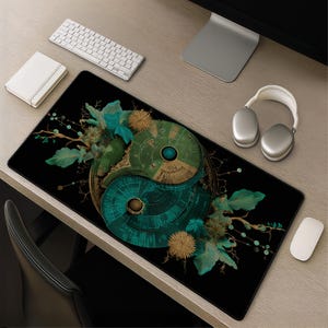 May include: Black rectangular desk mat featuring a teal and green Yin Yang design with floral accents. The mat has a detailed, intricate pattern and is surrounded by a keyboard, mouse, headphones, and a notebook.