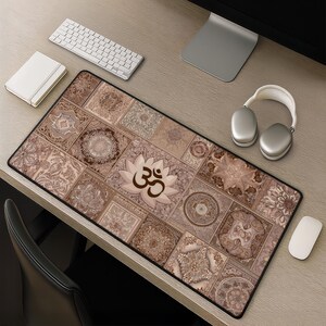 May include: A rectangular desk mat with a patchwork design in shades of brown and beige. The mat features a lotus flower with the Om symbol in the center. A white keyboard, mouse, and headphones are on the desk.