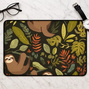 Könnte beinhalten: Rechteckiges schwarzes Mauspad mit einem Muster aus braunen Faultieren und grünen, orangefarbenen und gelben Blättern. Die Blätter und Faultiere sind vor einem dunklen Hintergrund platziert. Das Mauspad hat einen schwarzen Rand.