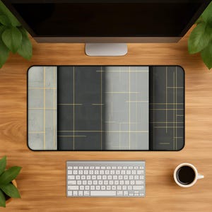 Puede incluir: Una alfombrilla de escritorio rectangular con un diseño segmentado de paneles alternos en gris claro y gris carbón oscuro. La superficie está decorada con una cuadrícula de finas líneas doradas que crean un patrón geométrico en toda la alfombrilla.