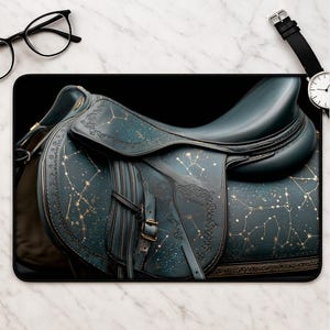 May include: A dark teal horse saddle featuring a gold celestial constellation pattern across its surface. The saddle includes integrated straps, buckles, and a contoured seat design, showcasing intricate star map detailing and fine gold line work.