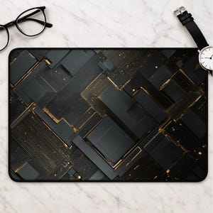 May include: A rectangular desk mat featuring a dark, abstract geometric pattern of matte black blocks and intricate gold circuit board lines. The design creates a layered, technical aesthetic with sharp angles and metallic gold accents throughout.