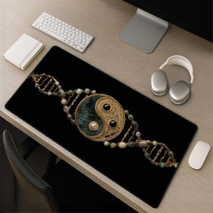 May include: Black rectangular mousepad featuring a gold-colored yin-yang symbol with a green center, black accents, and a pearl. The design is flanked by DNA-like strands with green and beige beads. A keyboard, headphones, and mouse are also visible.