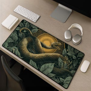 Peut inclure: Un tapis de bureau rectangulaire présentant une illustration détaillée d'un serpent enroulé aux écailles dans des tons de brun et de vert, entouré d'un feuillage vert foncé et d'un élément circulaire doré rappelant un soleil.
