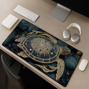 May include: A decorative mouse pad featuring a detailed golden turtle design on a dark blue background. The turtle has intricate patterns and is surrounded by a rocky texture. A white keyboard, mouse, and headphones are also visible.