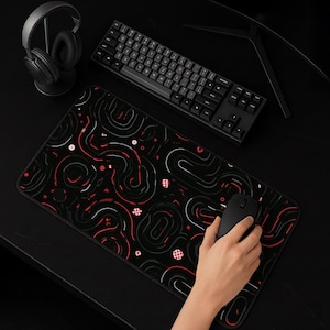 May include: A rectangular desk mat featuring a black background with a repeating pattern of abstract white and red curved lines and small red and white checkered circular accents. The mat is positioned under a black mechanical keyboard and mouse.