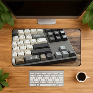 May include: A desk mat featuring a high-resolution print of a mechanical keyboard with a mix of cream, dark gray, and brown keycaps. The keyboard layout includes a large enter key, arrow keys, and various function keys, all set against a dark frame.
