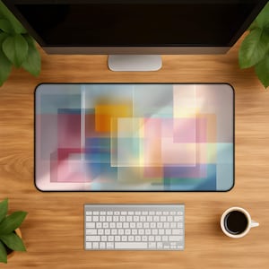 May include: A rectangular desk mat featuring a translucent, layered geometric pattern of overlapping squares and rectangles in soft shades of yellow, pink, blue, and white, with a black border, positioned on a wooden desk surface.