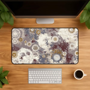 Puede incluir: Una alfombrilla de escritorio rectangular con un patrón abstracto de motivos circulares tipo mandala en tonos blanco, crema, rojo oscuro y oro mate, sobre un fondo moteado y nublado de tonos grises y blanquecinos con superficie lisa.