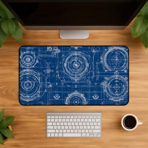 May include: A rectangular desk mat featuring a dark blue background with white technical blueprint illustrations of circular mechanical components, gears, and engineering schematics arranged in a repeating pattern across the entire surface.
