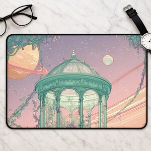 Può includere: Un tappetino da scrivania rettangolare con un'illustrazione dai colori pastello di un gazebo color ottanio intrecciato con viti. Lo sfondo raffigura un cielo stellato con due grandi pianeti con anelli nelle tonalità pesca e crema.