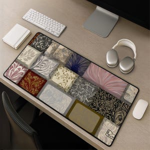 May include: A rectangular desk mat featuring a grid of various artistic patterns including floral motifs, swirling lines, and abstract textures in a palette of cream, black, gold, deep red, and soft pink, with a small logo in the bottom right corner.