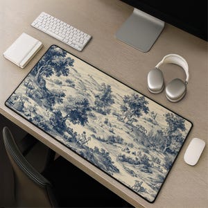 May include: A rectangular desk mat featuring a blue and cream toile de jouy pattern. The design depicts a pastoral landscape with rolling hills, scattered trees, and small figures of people and animals, including a person riding a horse in the center.