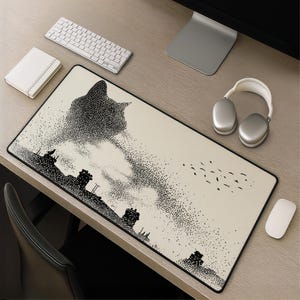 May include: A rectangular desk mat featuring a cream-colored surface with a black stippled illustration of a large cat head looming over a cityscape with rooftops and a flock of birds flying in the distance, finished with a black stitched edge.