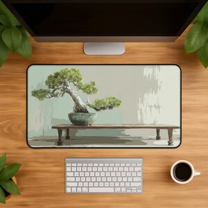 May include: A rectangular desk mat featuring a printed illustration of a green bonsai tree in a ceramic pot resting on a wooden bench. The background is a light, muted sage green with a textured, painterly effect. The mat has a black border.