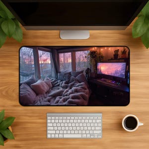 May include: A rectangular desk mat featuring a cozy room scene with a computer setup. The scene includes a bed with pillows and a fluffy blanket, a computer monitor, keyboard, and plants. The background shows a sunset view through windows.