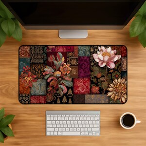 Puede incluir: Una alfombrilla de escritorio rectangular con un diseño de patchwork oscuro e intrincado con varios motivos florales, incluyendo una flor de loto rosa claro, flores de color rojo intenso y patrones dorados sobre un fondo negro y rojo oscuro.