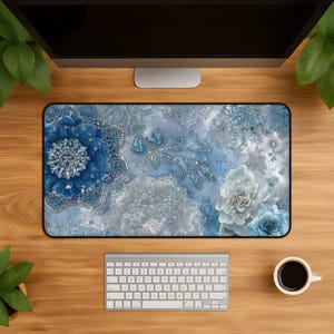 Puede incluir: Una alfombrilla de escritorio rectangular con un estampado digital detallado de patrones florales en capas azules y blancas, filigrana plateada intrincada y acentos brillantes sobre un fondo azul claro y blanco marmolado.