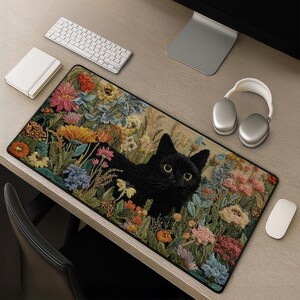Può includere: Un tappetino da scrivania rettangolare con un'illustrazione dettagliata di un gatto nero immerso in un giardino vivace di fiori colorati, tra cui fiori rosa, arancioni, gialli e blu. Il tappetino presenta un bordo nero e una superficie liscia.