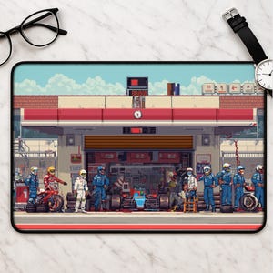 May include: Pixel art mousepad featuring a race car pit stop scene. The design includes a garage with a red and white awning, a race car, and crew members in blue and white uniforms. The background shows a blue sky with clouds.