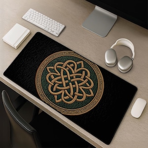 May include: A rectangular desk mat featuring a black textured background and a large central circular emblem. The emblem displays an intricate gold-colored Celtic knot design set against a dark green, pebbled-texture circular field.