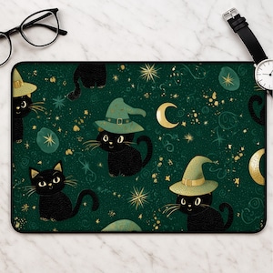 Op de afbeelding: Een rechthoekige bureaumat met een donkergroene achtergrond en een herhalend patroon van zwarte katten, waarvan sommige lichtgroene puntmutsen dragen. Het ontwerp bevat goudkleurige halve manen, sterren en wervelende hemelse accenten.