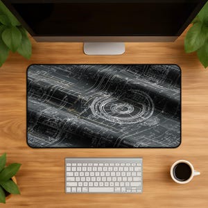 Könnte beinhalten: Eine rechteckige Schreibtischunterlage mit einem dunkelgrauen und schwarzen technischen Blaupausen-Design, das komplizierte weiße Linienführungen, geometrische Muster und ein markantes kreisförmiges schematisches Element aufweist.