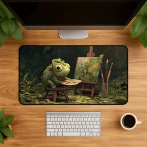 May include: A rectangular desk mat featuring a green chameleon sitting on a small wooden stool, holding a paint palette. Next to the chameleon is a canvas on a wooden easel and a glass jar containing several paintbrushes, all set in a forest.